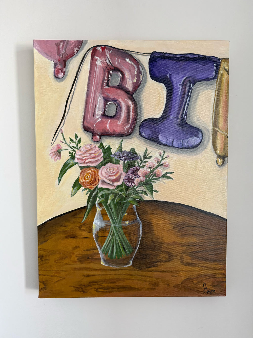 painting of decorative setup with balloon letters 'BI' and part of two other balloons and a vase of pink, purple, orange flowers and greenery in clear vase on a wooden table. view of painting on wall. 