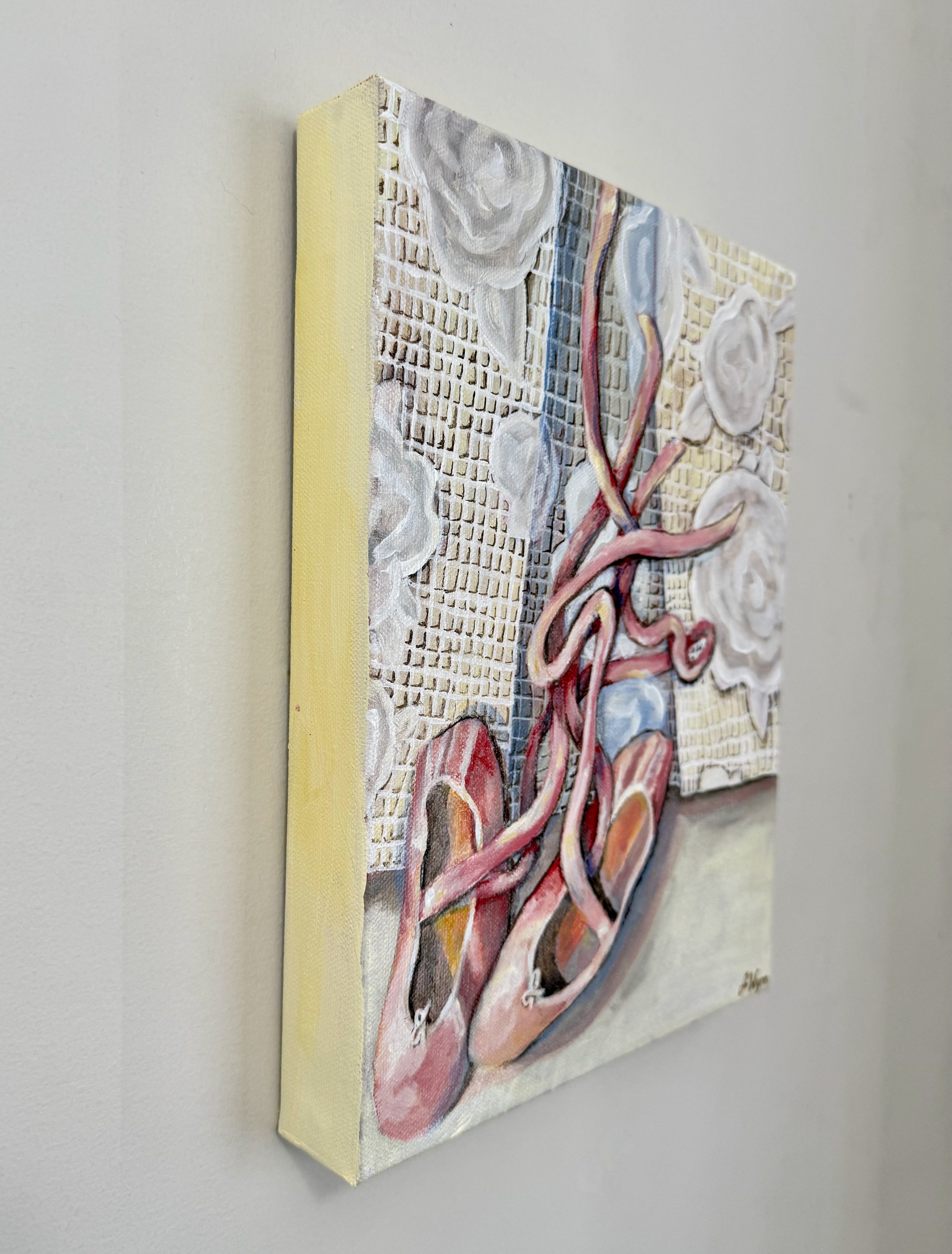 painting of pink ballet shoes with ribbons on a white lace textured background. view of painting from the side.